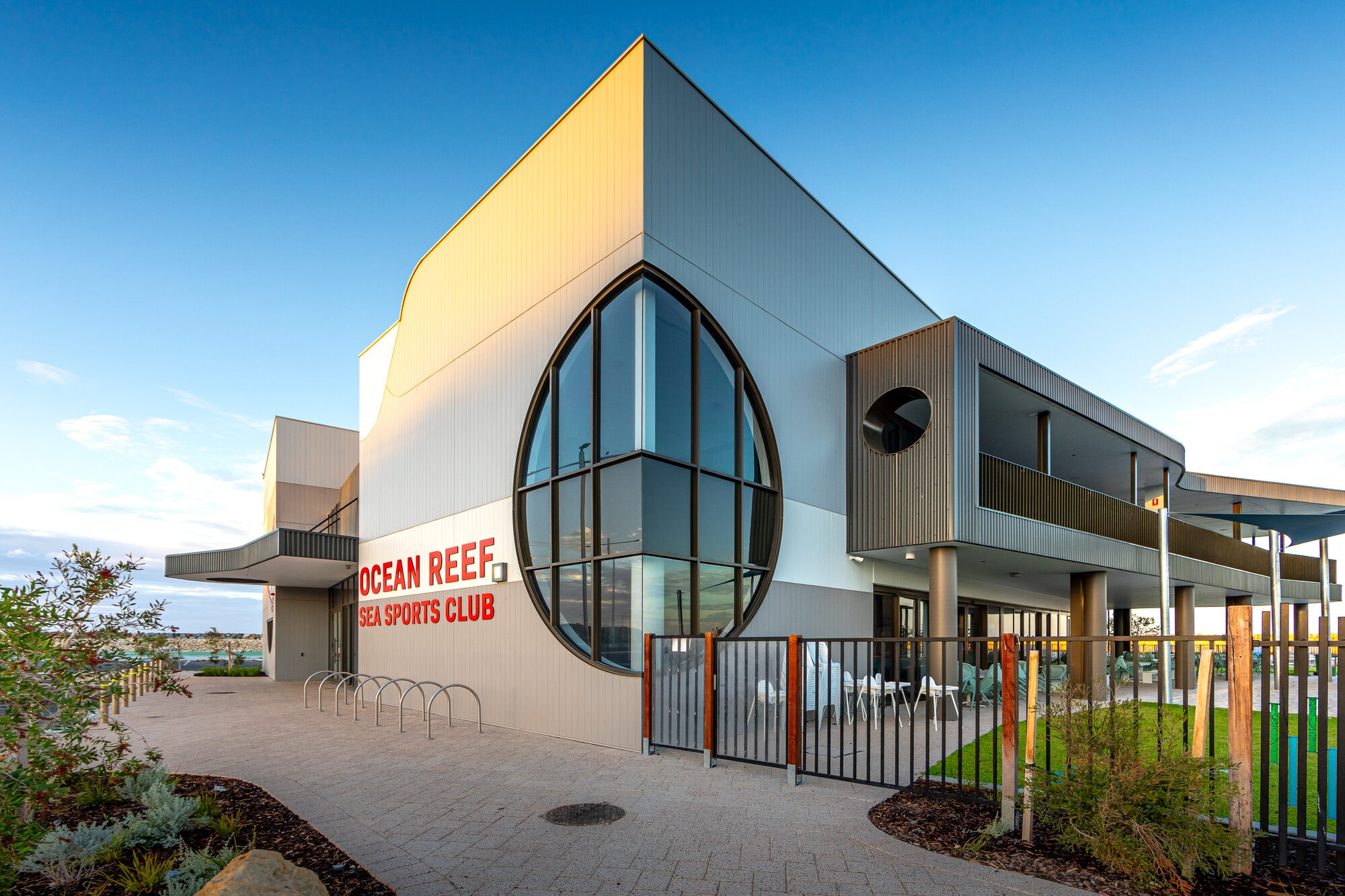 Ocean Reef Sea Sports Club exterior facade with large curved feature window, club signage, fencing and marina-side paving.